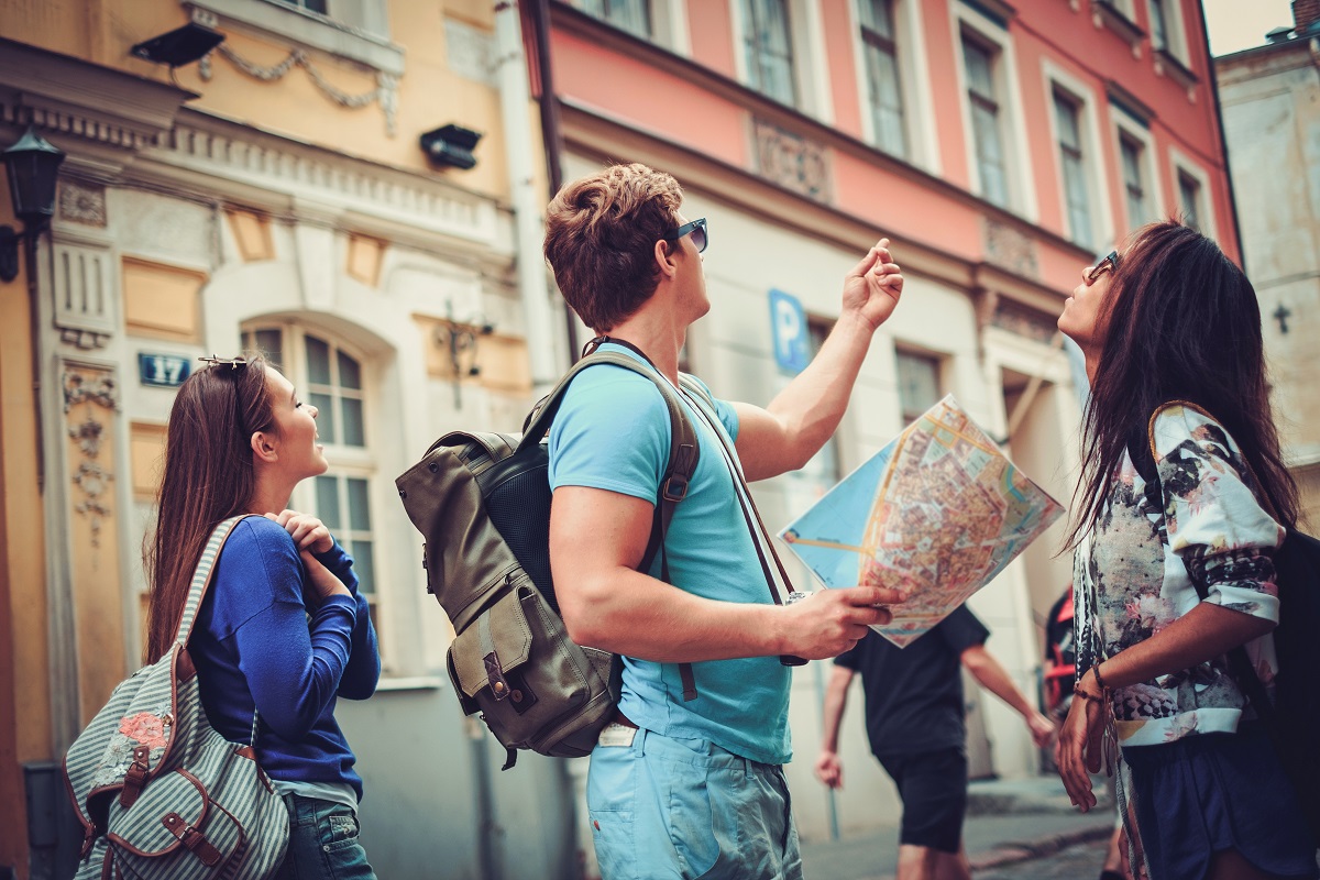 Multi ethnic friends tourists with map in old city.