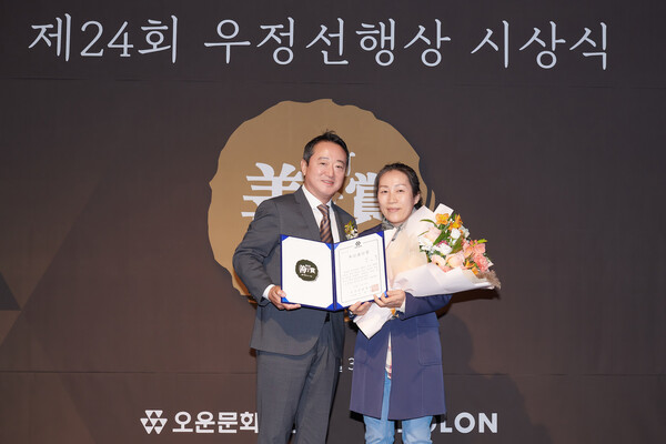 이웅열 오운문화재단 이사장(왼쪽)이 우정선행상 대상을 수상한 김선자(53) 씨와 기념사진을 촬영하고 있다.(사진제공=코오롱)