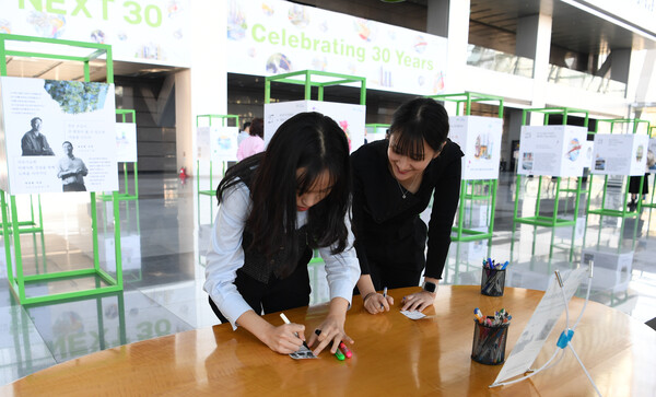 포스코이앤씨가 30주년을 맞아 30개의 성공스토리를 담은 전시회를 개최했다. 포스코 직원들이 즉석사진에 응원메시지를 적고 있다. (사진제공=포스코이앤씨)