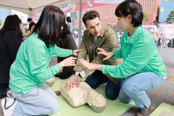 서울역 광장에서 진행된 ‘희망브리지 응급처치 체험부스’에서 외국인 참여자가 희망브리지 관계자의 안내에 따라 심폐소생술을 배우고 있다.(사진제공=희망브리지)