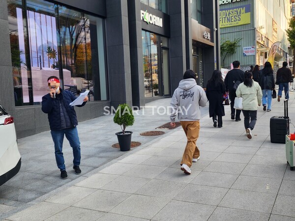 아이에스동서의 할인분양을 규탄하는 울산뉴시티 비대위 관계자 옆으로 시민들이 지나가고 있다. 출처=김종현 기자