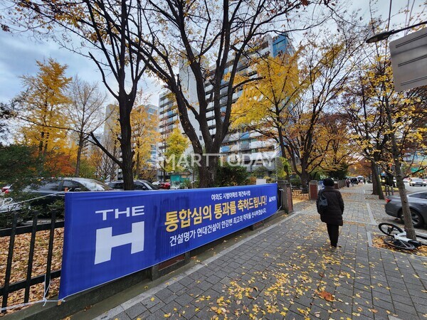 현대건설의 '여의도 시범아파트 재건축 통합심의 축하' 플랜카드가 걸린 시범아파트 입구 부근을 한 시민이 지나가고 있다. 출처=김종현 기자